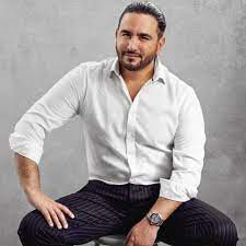 Picture of Dr. Mario Alvarenga, M.D., sitting on a chair, wearing a white shirt with rolled-up shirt sleeves, smiling, and looking directly at the camera.